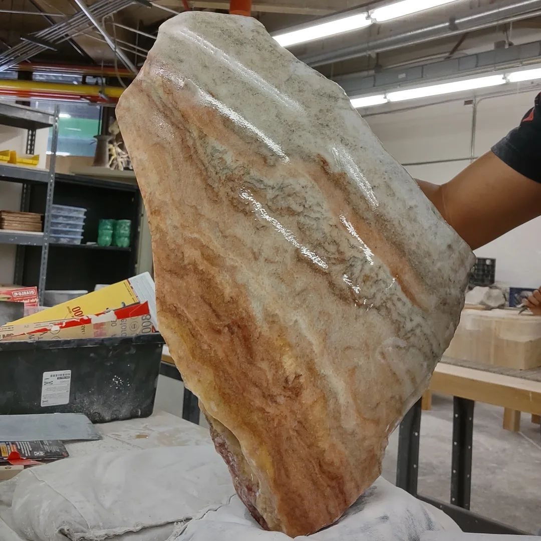 Utah fine artist sculptor Byron Ramos holding a polished slab of honeycomb calcite up to the light